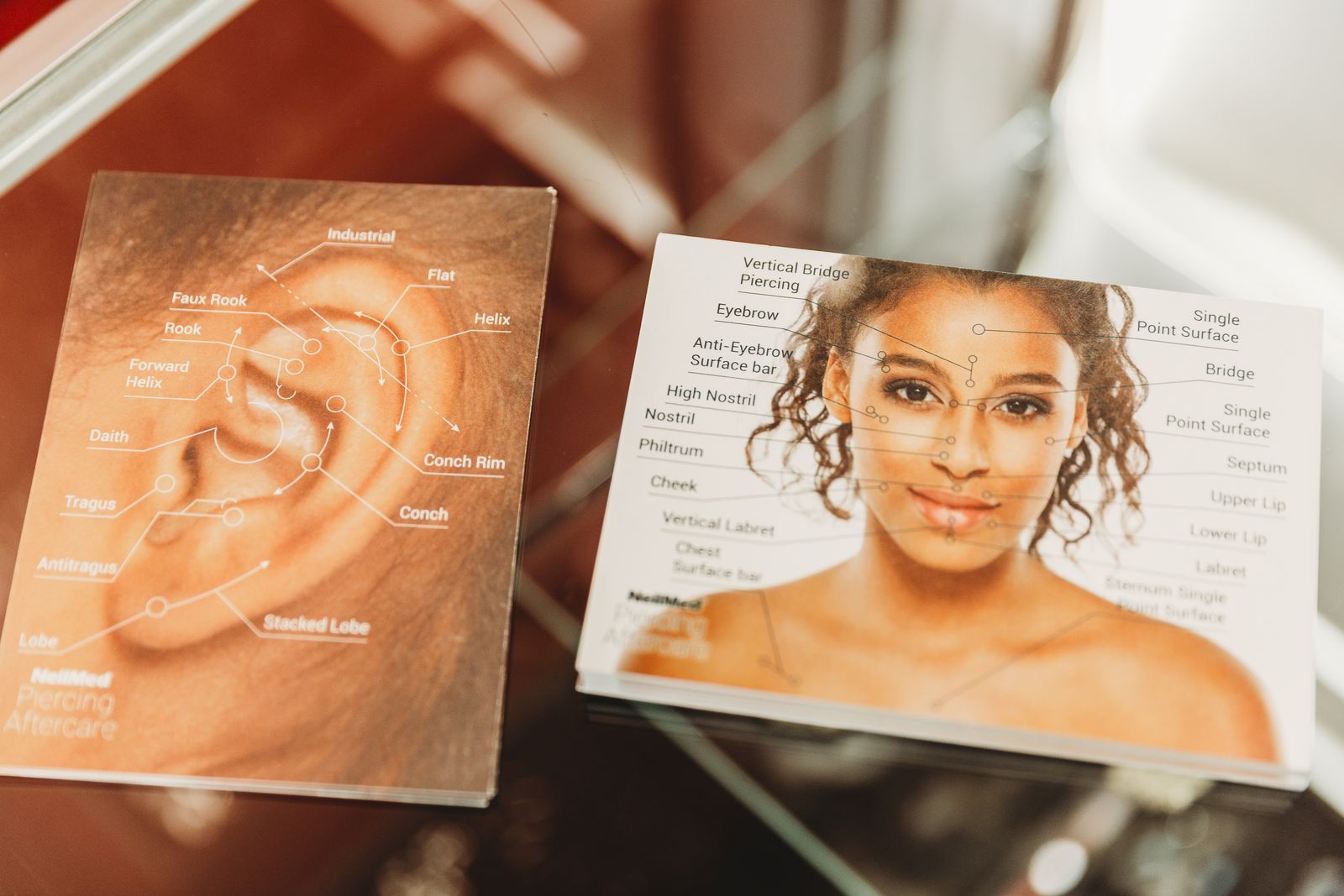 Ear and facial piercing anatomy charts at the counter
